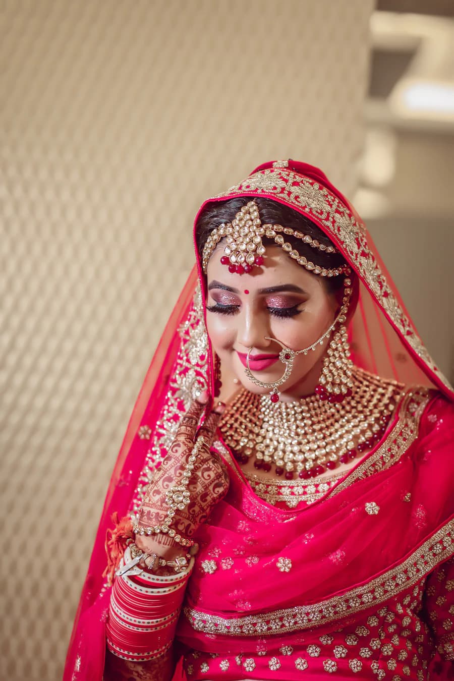 Bride in red and gold looking down and smiling