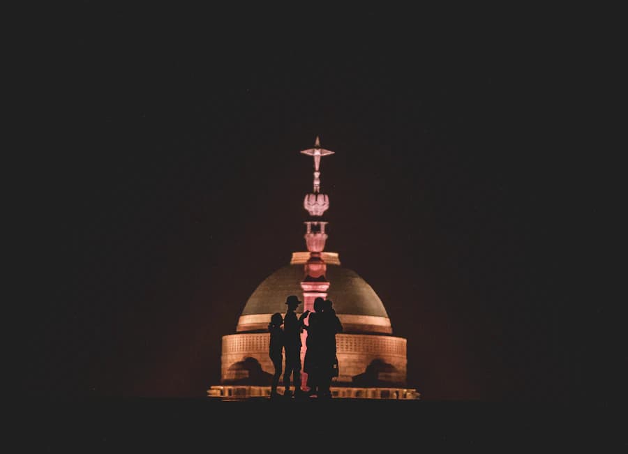 Couple silhouetted against a lit monument at night